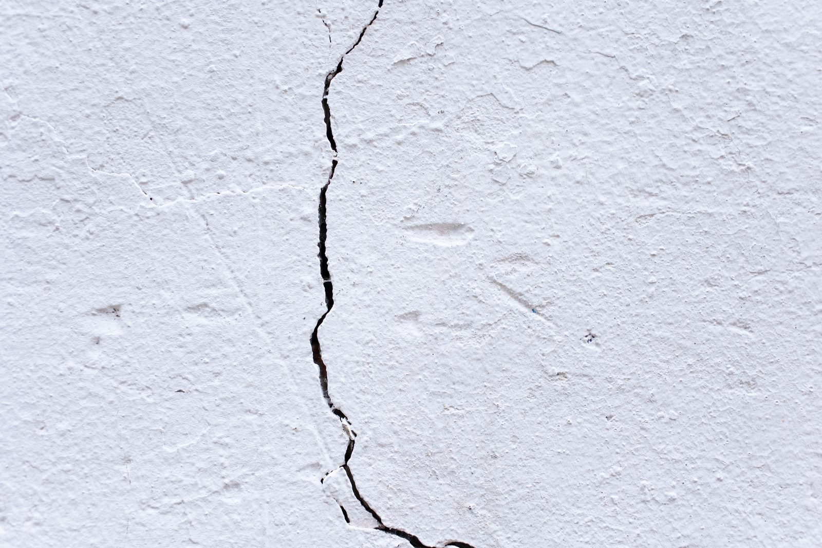 Vertical crack running through a painted plaster exterior wall
