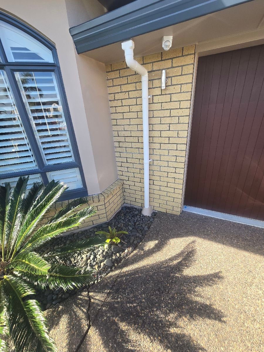 Sunny home entrance showing downpipe and drainage
